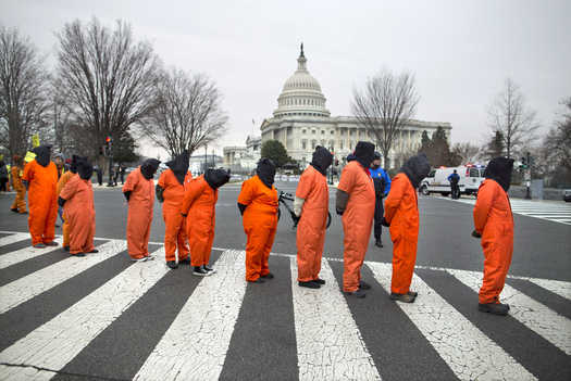 Demonstrators dressed as detainees march past the Capitol building